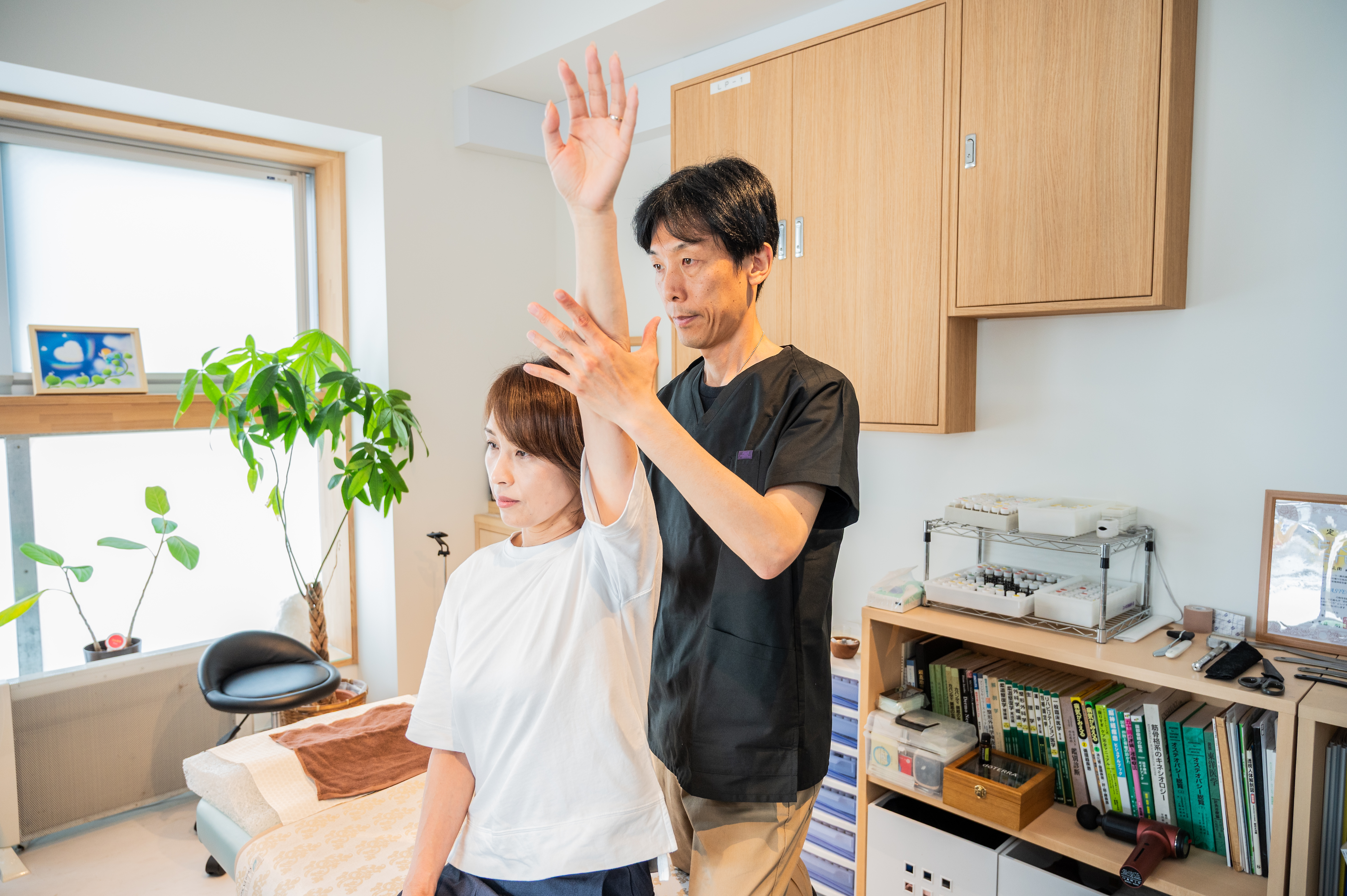 ベッドで施術を受ける女性と施術者