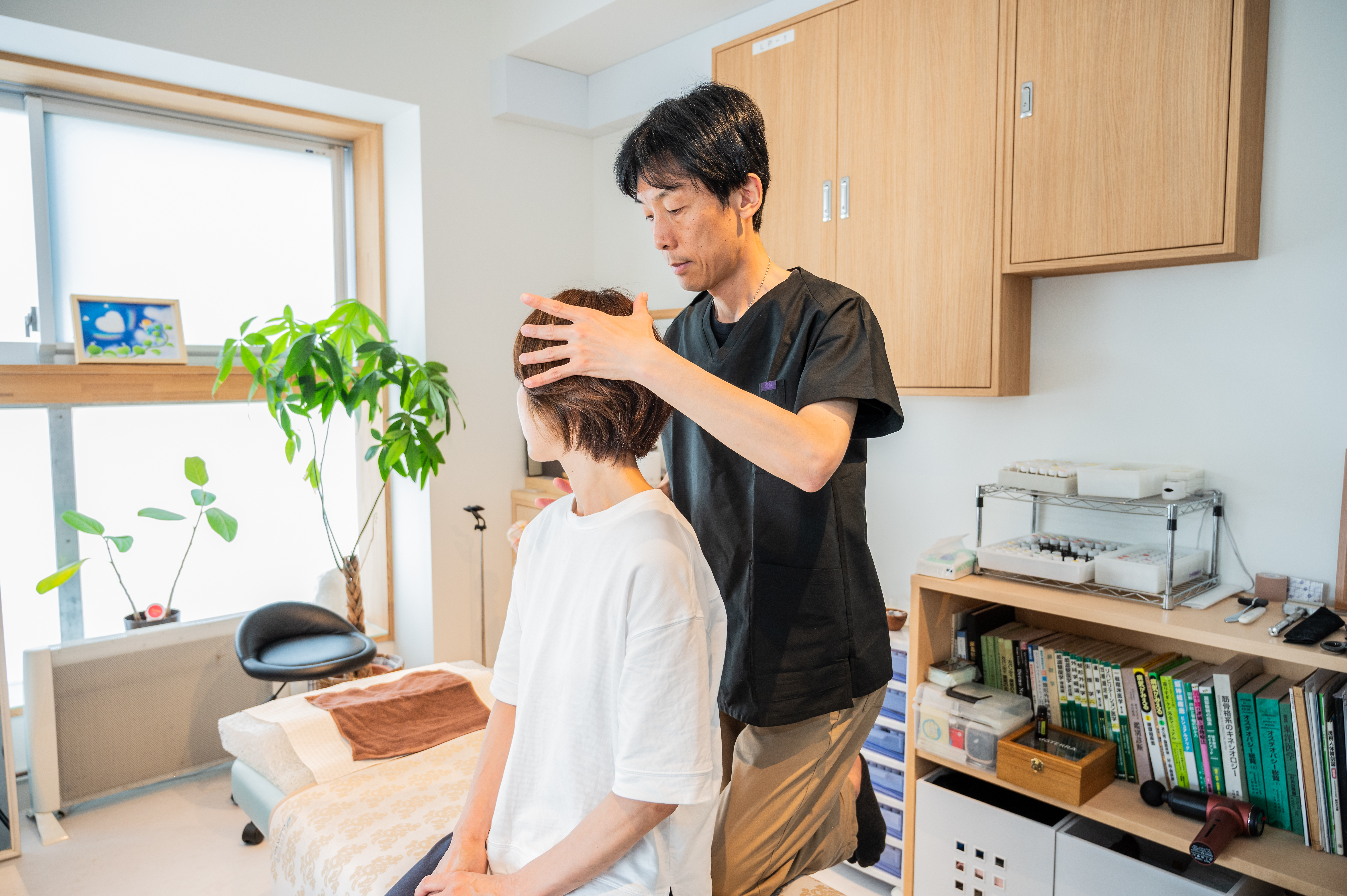 ベッドで施術を受ける女性と施術者